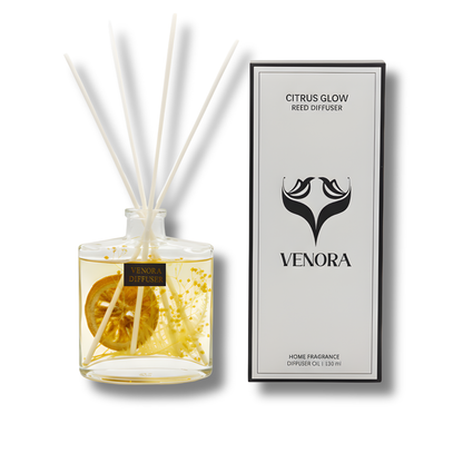 Luxury Citrus Glow reed diffuser by Venora with citrus-basil fragrance, dried botanicals, and orange slice in a clear glass bottle on a clean white background.