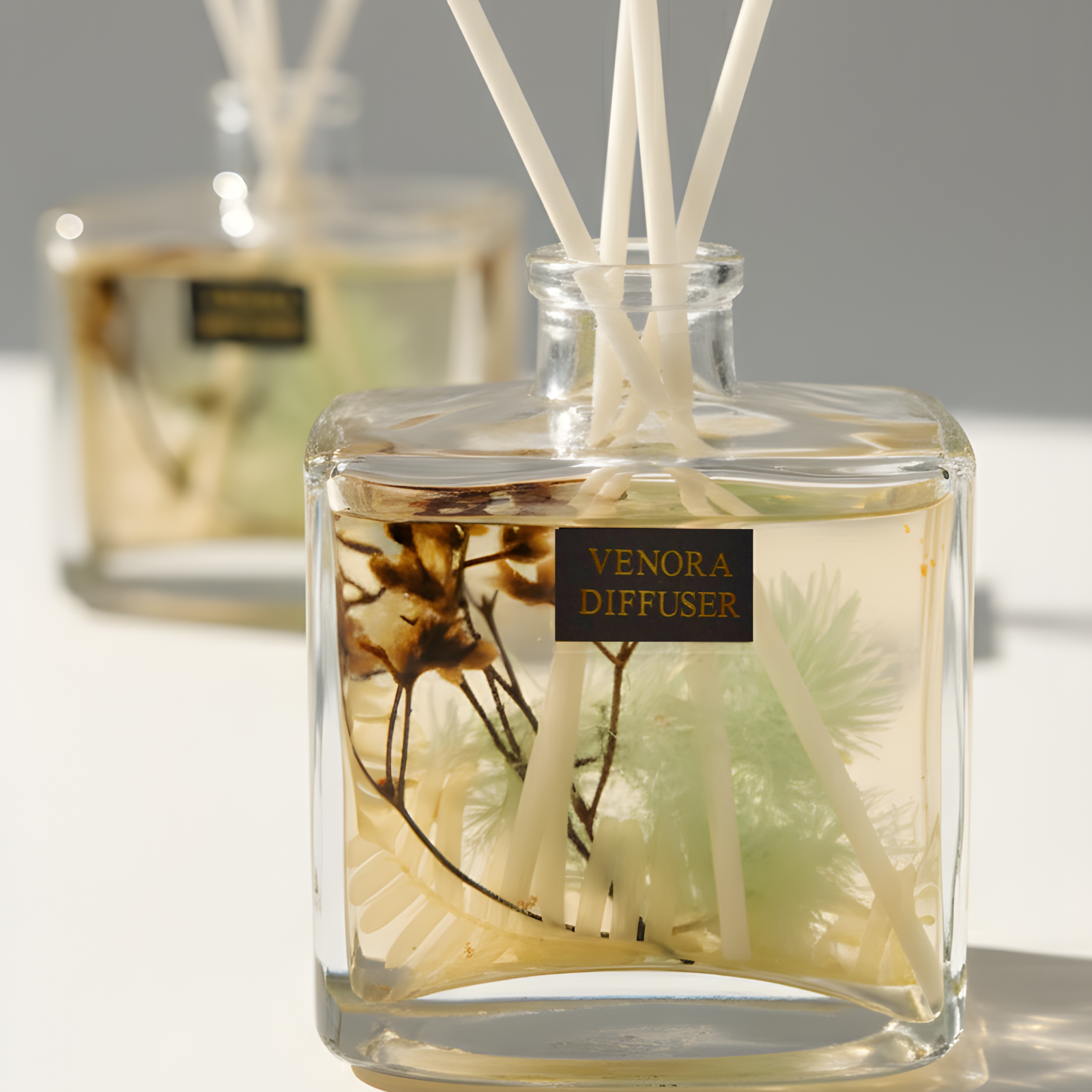 Cinematic close-up of Venora Golden Peach diffuser reeds and dried botanicals with warm lighting and elegant glass reflections.
