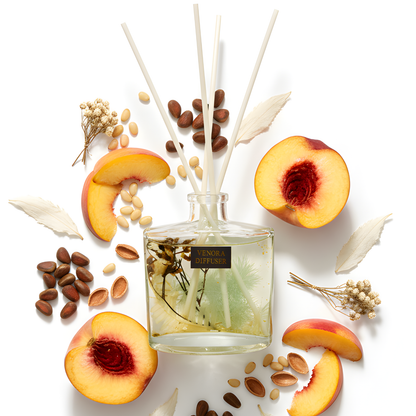 Minimalist flatlay of Venora Golden Peach diffuser with peach, pine, white tea, and botanical elements arranged in a luxury fragrance layout.
